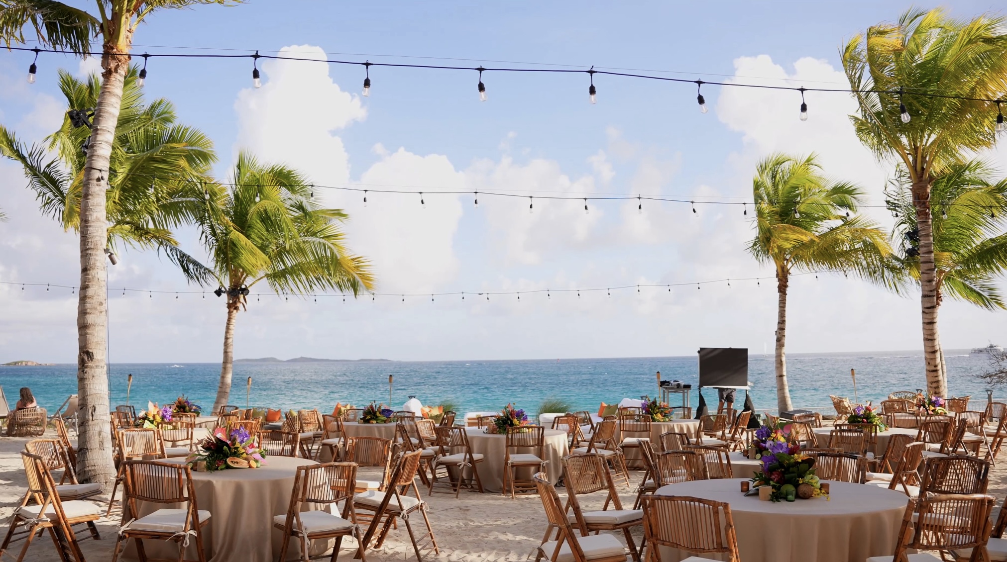 Elegant beach dinner setup with string lights and palm trees